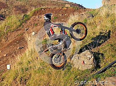 Trial motorcyclist standing on bike wheelie Editorial Stock Photo