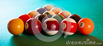 Triangle of multicolored billiard balls with numbers on the pool table. Sports game billiards on a green cloth. Banner Stock Photo