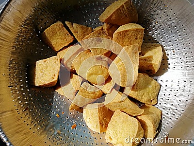 Triangle shape of Fried Tofu in colander for Oil filter. Raw materials of vegetarian food Stock Photo