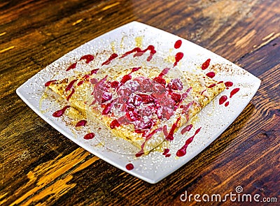 Triangle shaped dessert crepe with berries, and raspberry sauce. Stock Photo