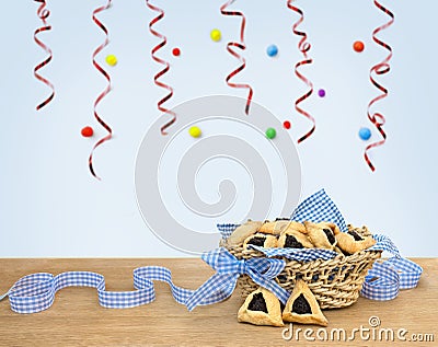 Triangular cookies with poppy seeds hamantasch or aman ears and blue ribbon on wooden table on blue background Stock Photo