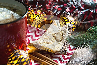 Triangular cookies with powdered sugar and cinnamon on a napkin with a zigzag pattern in the Christmas decor. Red coffee mug with Stock Photo