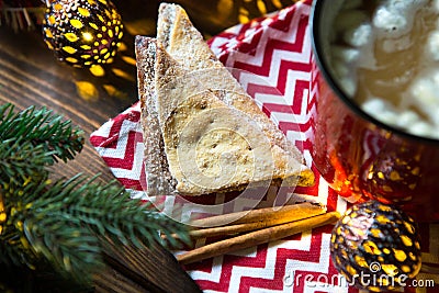 Triangular cookies with powdered sugar and cinnamon on a napkin with a zigzag pattern in the Christmas decor. Red coffee mug with Stock Photo