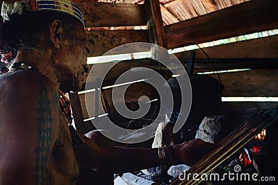 Tribal elder Toikot drying poisoned arrows over the fire at his rainfor Editorial Stock Photo