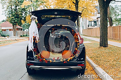 Trick or trunk. Black car trunk decorated for Halloween. Autumn fall decor with red pumpkins and yellow leaves for traditional Stock Photo