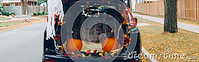 Trick or trunk. Black car trunk decorated for Halloween. Autumn fall decor with red pumpkins and yellow leaves for traditional Stock Photo