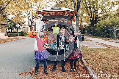 Trick or trunk. Siblings brother and sisters celebrating Halloween in trunk of car. Children kids boy and girls preparing for Stock Photo