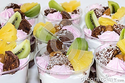 Trifle cake in glass, chocolate biscuit cakes with cream cheese and blueberry jam, decorated with meringue, fruit and candy Stock Photo