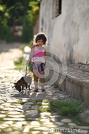 Trinidad, Cuba, August 16th, 2018: Little girl playing with her dog on the street of Trinidad Editorial Stock Photo