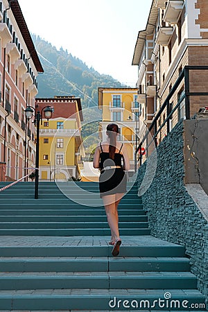 Trip to Russia. Rear view of a female tourist in black shorts climbing the stairs in Sochi, Krasnaya Polyana. Beautiful city on Editorial Stock Photo