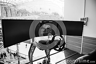 Triple screen setup with steering wheel and pedals racing games Editorial Stock Photo