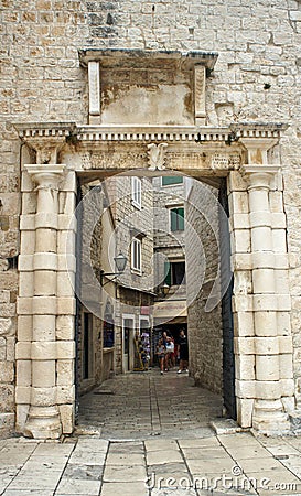 Trogir, Croatia - 07/25/2015 - Stone gate in the street of old town, beautiful architecture, sunny day Editorial Stock Photo