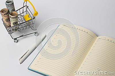 Trolley with money, open notebook with a pen for writing on a white background. diet concept recipe, selective focus Stock Photo