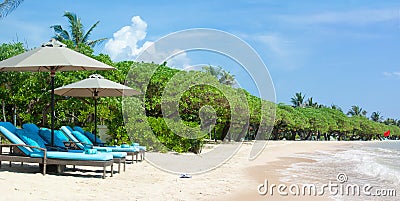 Tropical beach background with loungers and tents, green trees and white sand Stock Photo