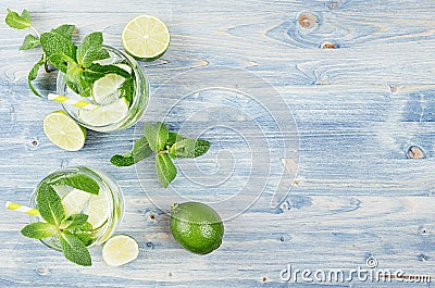 Tropical fresh cold cocktail gin tonic with mint, lime, ice, straw on light blue shabby wood board, border, top view. Stock Photo