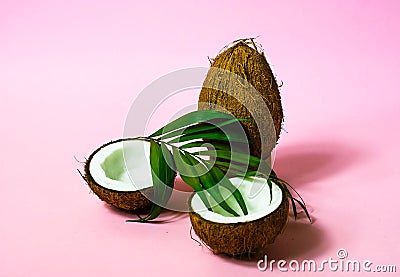 Tropical fruit whole and halves of coconut.Creative layout made of coconuts and leaves on pink background.. Food concept. Stock Photo