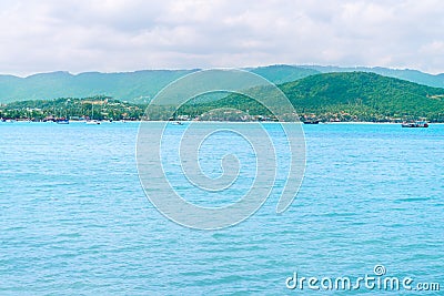 Tropical green hilly island shore and blue calm clean sea Stock Photo