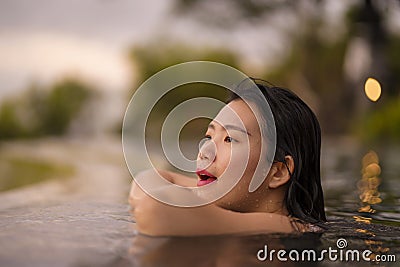 Tropical holidays lifestyle portrait of young beautiful and happy Asian Korean woman in bikini enjoying sunset at amazing jungle Stock Photo