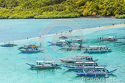 Tropical island landscape with lots of bangca traditional philippines boats anchored at the shore full of tourists, Vigan Island, Stock Photo