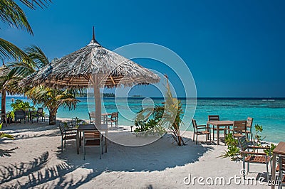Tropical island with palm trees and amazing vibrant beach in Maldives. Parasol in sea tropical Maldives romantic atoll island Stock Photo