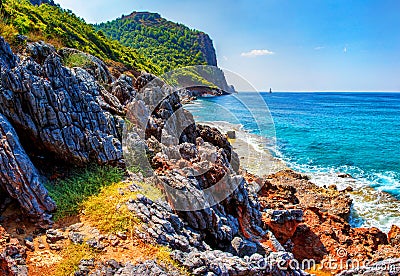 Tropical landscape of rocky coastline with mountains and blue sea water on clear sunny summer day Stock Photo