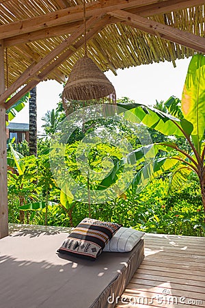 Tropical resort with lounge place with pillows. Holiday villa with garden and comfortable patio. Empty exotic resort. Stock Photo