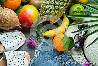 Tropical Summer Fruits Pineapple Mango Bananas Coconut on Large Palm Tree Leaf. Women Jeans Shorts Slippers Hat Sunglasses Stock Photo