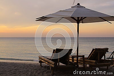 Tropical umbrella and bamboo long chairs on beach Stock Photo