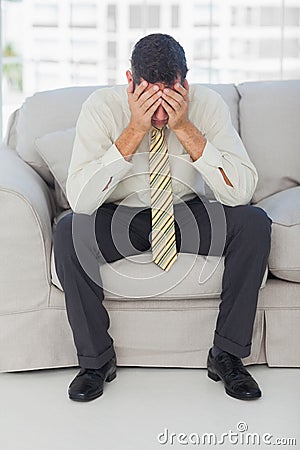 Troubled businessman sitting on sofa Stock Photo
