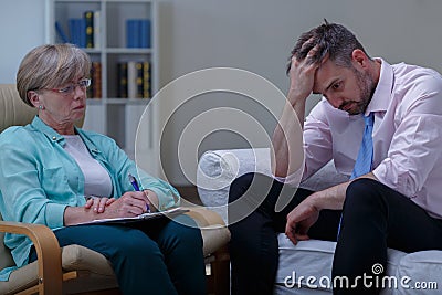 Troubled businessman talking with psychiatrist Stock Photo