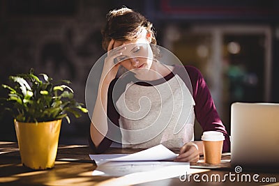Troubled young female designer reading paper at coffee shop Stock Photo