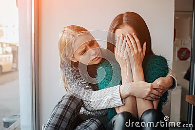 Troubled young girl comforted by her friend. Woman supporting the girl Stock Photo