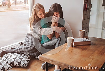 Troubled young girl comforted by her friend. Woman supporting the girl Stock Photo