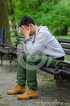 Troubled young man sitting in the park Stock Photo