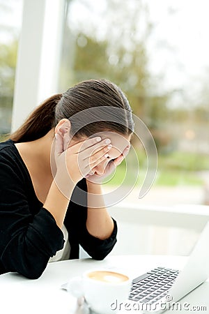 Troubled young woman holding her hands to her eyes Stock Photo