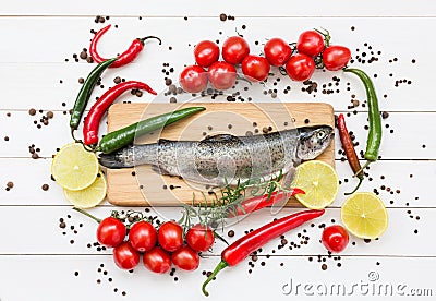Trout fish on wooden cutting board with cherry tomatoes Stock Photo