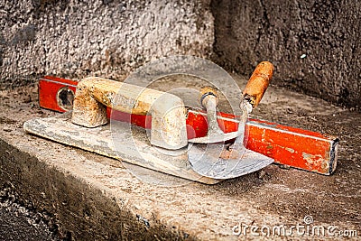 Trowels and other masonry tools on a concrete wall Stock Photo