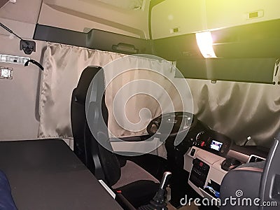 A truck driver is going to sleep in his cabin after working long hours on routes for a long time. The cab of the truck at night, Stock Photo