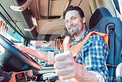 Truck driver sitting in cabin giving thumbs-up Stock Photo