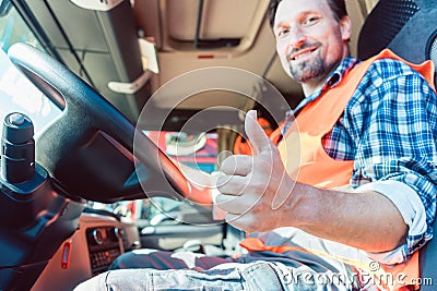 Truck driver sitting in cabin giving thumbs-up Stock Photo