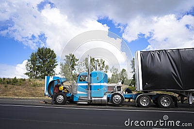 Truck drivers repairing big rig semi truck with open hood right Stock Photo