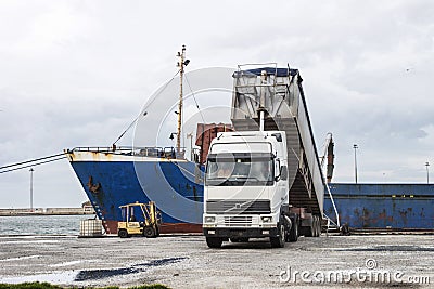 Truck loading grain on ship Stock Photo