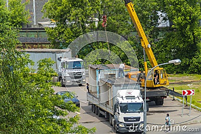 A truck with a mobile crane removes and loads a container with a temporary building Editorial Stock Photo