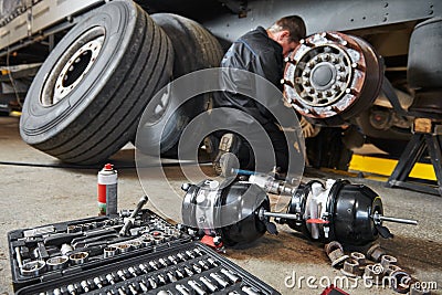 Truck repair service. Mechanic works with brakes in truck workshop Stock Photo