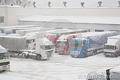 Trucks loading at warehouse and transport terminal. Parking in severe winter weather storm. Prohibition of traffic in heavy snow Stock Photo