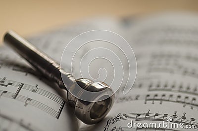 Trumpet mouthpiece on sheet music book Stock Photo