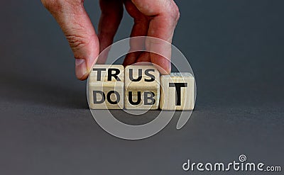 Trust or doubt symbol. Businessman flips wooden cubes and changes the word doubt to trust. Beautiful grey background, copy space. Stock Photo