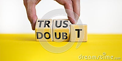 Trust or doubt symbol. Businessman turns wooden cubes and changes the word doubt to trust. Beautiful yellow table, white Stock Photo