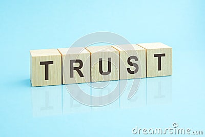 wooden blocks with the word Trust, blue background Stock Photo