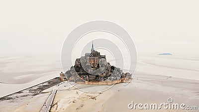 Truteń lata z lewej strony nad Mont saint michel wyspa z opactwem i drogą z turystami podczas niskiego przypływu na mglistym dniu zdjęcie wideo Truteń lata z lewej strony nad Mont saint michel wyspa z opactwem i drogą z turystami podczas niskiego przypływu na mglistym dniu zdjęcie wideo